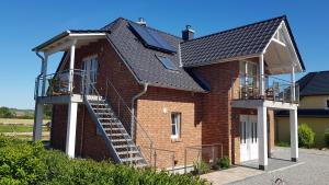 a house with a black roof and a staircase on it at Ferienwohnung Rügen 1, Alt Reddevitz 108, Insel Rügen, mit Kamin, Sauna Nutzung möglich in Middelhagen