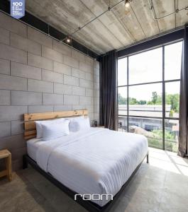 a bedroom with a large bed with a large window at Owl Poshtel Kanchanaburi in Kanchanaburi City