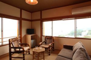 a living room with a couch and chairs and windows at Beach Commune Simploose (Adult Only) in Ito