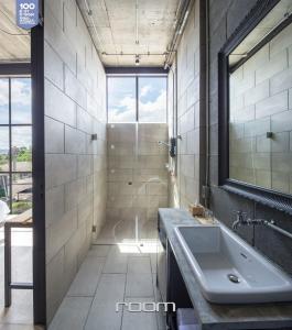 a bathroom with a sink and a shower at Owl Poshtel Kanchanaburi in Kanchanaburi