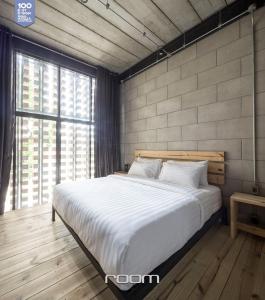 a bedroom with a large bed and a large window at Owl Poshtel Kanchanaburi in Kanchanaburi