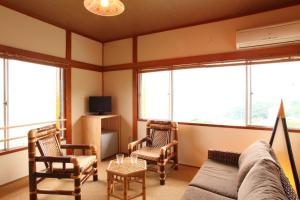 ein Wohnzimmer mit einem Sofa, Stühlen und Fenstern in der Unterkunft Beach Commune Simploose (Adult Only) in Ito