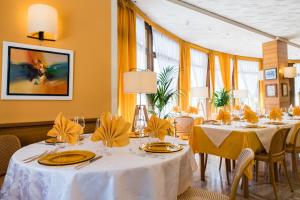 a restaurant with white tables and chairs and yellow walls at Albergo Milano Snc in Lanzo dʼIntelvi