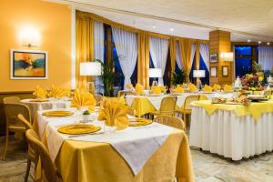 una sala banchetti con tavoli con biancheria gialla di Albergo Milano Snc a Lanzo dʼIntelvi