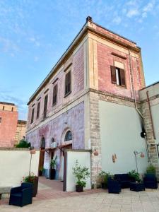 um antigo edifício de tijolos com duas portas de garagem e plantas em Casa di Marco em Galatina