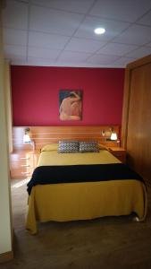 a bedroom with a yellow bed with a red wall at Hostal Doña Juana in Avila