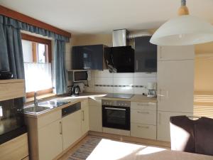 a kitchen with white cabinets and a sink and a window at Ferienwohnung Embacher in Söll