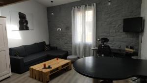 sala de estar con sofá negro y mesa en Duplex au Coeur de Lunel, en Lunel