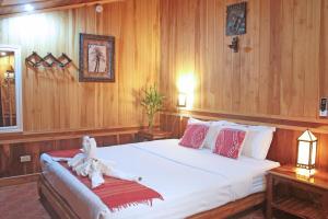 a bedroom with a large white bed with wooden walls at Apple Guesthouse in Luang Prabang