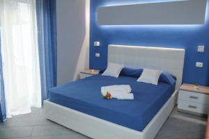 a blue bed with towels and flowers on it at Apartments " Le Ginestre" in Acireale