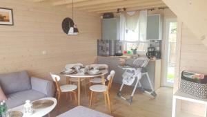 a room with a table and chairs and a kitchen at RODZINKA B&M Całoroczne domki w stylu skandynawskim , podgrzewany basen z mobilnym zadaszeniem in Niechorze