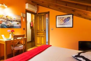 1 dormitorio con pared de color naranja, cama y escritorio en Alojamiento Bernabales, en Pámanes