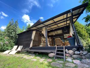 a tiny house with a porch and a ladder at Akmenos Villas & Bungalow in Bražuolė