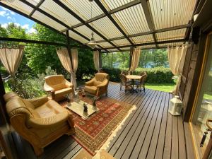 un porche cubierto con muebles en la cubierta en Akmenos Villas & Bungalow, en Bražuolė