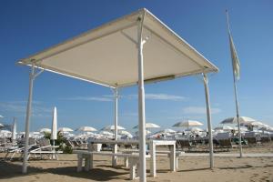 un gruppo di tavoli e sedie su una spiaggia con ombrelloni di Hotel Kim a Rimini