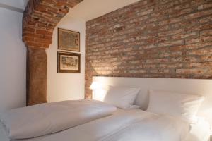 a bedroom with a brick wall and a white bed at Brauereigasthof & Hotel Kapplerbräu in Altomünster