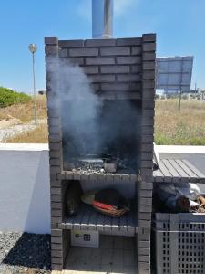 a grill with smoke coming out of it at Casa da Praia em Porto Côvo in Porto Covo