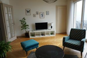 a living room with a tv and two chairs and a table at Maujobia 31 in Neuchâtel