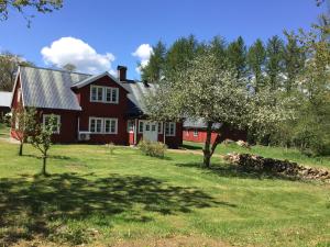 una casa roja con un árbol en el patio en Stuga nära Ullared en Ullared