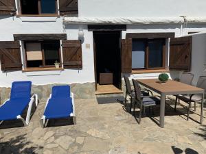 un patio con una mesa de madera y sillas azules en Casa Rural Aldea Chica, en Los Caños de Meca