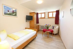 a small room with a bed and a table with flowers at Landhaus Schwaben in Bad Wiessee