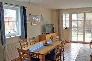 a dining room with a table and chairs and a television at Ferienhaus das Blaue Haus WS-9a in Born