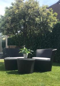 a black couch sitting in the grass with a potted plant at VILLA FER-GUY " Beeldige Suite met parking, nabij strand en casino" in Knokke-Heist
