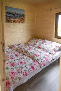 a bed in a wooden room with a floral blanket at Balti Domki Letniskowe in Dębina