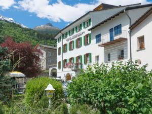 un edificio en un pueblo con montañas en el fondo en Altavilla, Rooms & Breakfast, en Poschiavo