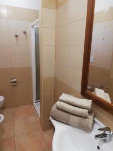 uma casa de banho com um lavatório e um chuveiro com toalhas em Villa Le Site em Racale