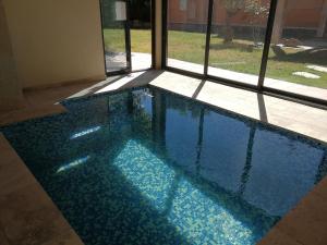 a blue swimming pool in a room with a window at L'isle verte in LʼIsle-sur-la-Sorgue