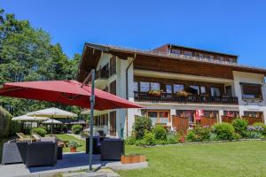 バート・ウィーゼにあるLandhaus Schwabenの赤い傘とテーブルと椅子のある建物