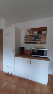 una cucina con armadi bianchi e un forno a microonde su un bancone di Steepleview House, Schwarzwaldblick Apartment - spacious & peaceful a Bad Peterstal-Griesbach