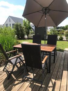 a wooden table and chairs with an umbrella on a deck at 2-Zimmer-Wohnung bei Nürnberg mit S-Bahn-Anschluss in Postbauer-Heng