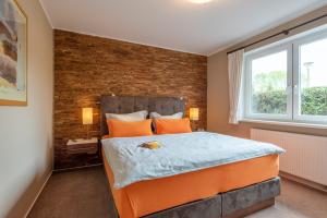 a bedroom with an orange bed and a brick wall at Ferienhaus Lütten Kulli - 1 in Zingst