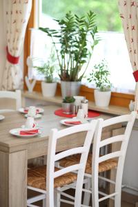 mesa de comedor con 2 sillas blancas y plantas en Landhaus Schwaben, en Bad Wiessee