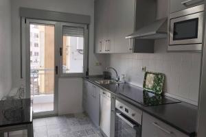 a white kitchen with a sink and a window at Campania in Ourense