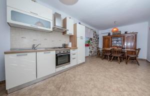 eine Küche mit weißen Schränken und ein Esszimmer in der Unterkunft Holiday House Predrag in Rab + 20 Fotos
