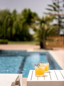 dos bebidas en una mesa junto a una piscina en Tsourlakis Residence, an oasis of tranquility, By ThinkVilla, en Pigi