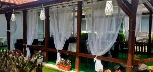 a screened in porch with white curtains and flowers at Guest Rooms Simona in Opanets