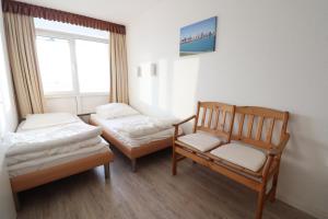 a room with two beds and a chair and a window at Frische Brise Sahlenburg in Cuxhaven