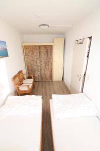 ein Zimmer mit 2 Betten und einem Stuhl darin in der Unterkunft Frische Brise Sahlenburg in Cuxhaven