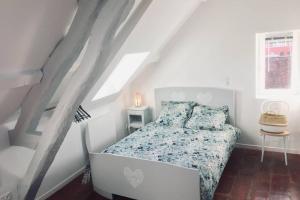 ein weißes Schlafzimmer mit einem Bett im Dachgeschoss in der Unterkunft TONNERRE grand studio de charme au coeur de la ville in Tonnerre