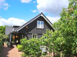 a black house with a white window and trees at Uniek houten huis nabij bos en plassen in Hollandsche Rading