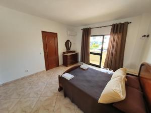 - une chambre avec un lit, un canapé et une fenêtre dans l'établissement Algarve Villa Albufeira Altos dos Caliços, à Albufeira