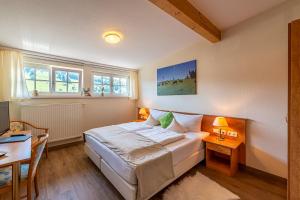 Schlafzimmer mit einem Bett, einem Schreibtisch und Fenstern in der Unterkunft Hotel Neudeck in Oberstaufen