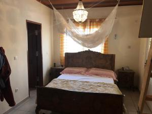 a bedroom with a bed with a chandelier and a window at VILLA MANGA in Yaoundé