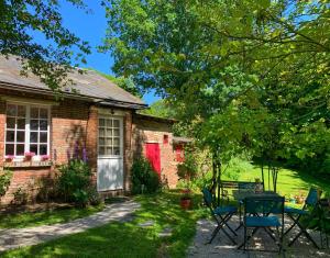 una casa in mattoni con una porta rossa e un tavolo con sedie di Les Jardins de MaLisa a Ferrières-la-Verrerie