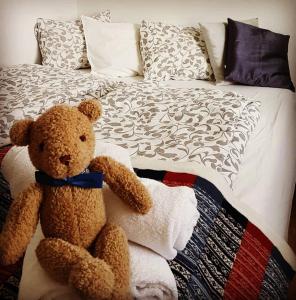 un oso de peluche marrón sentado en una cama en Móra guesthouse, en Birkimelur 