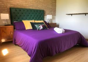 ein Schlafzimmer mit einem lila Bett mit einem grünen Kopfteil in der Unterkunft B&B Tenuta della Duchessa in Porto Viro